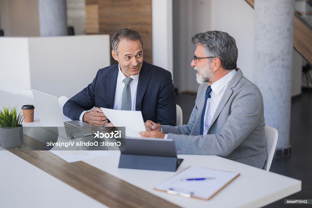 two businessmen reviewing paperwork and collaborating at a modern office table