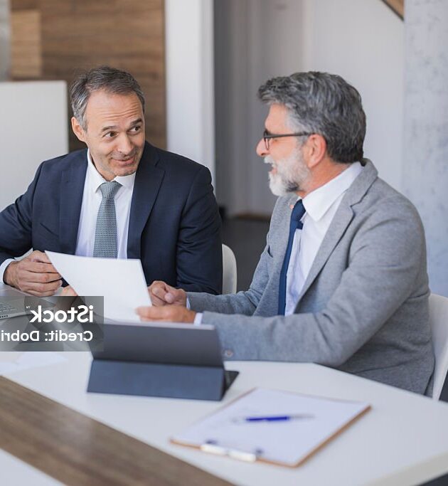 two businessmen reviewing paperwork and collaborating at a modern office table